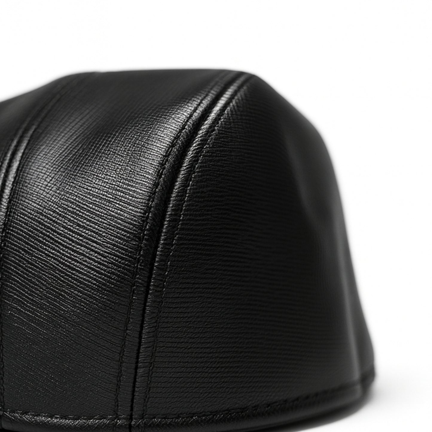 Black faux leather flat cap with a structured low crown , stiched curved in the middle and an adjustable round back photographed on a white background.