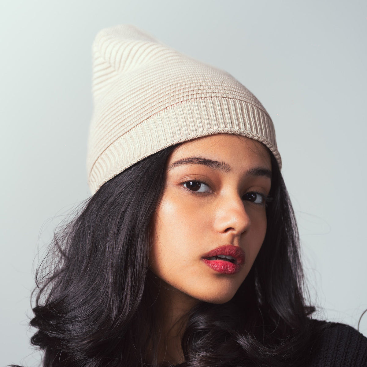 Woman wearing a beige beanie against a light gray background