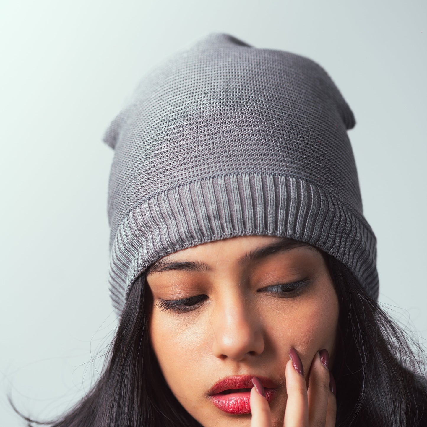 Woman wearing a gray knit beanie against a light background