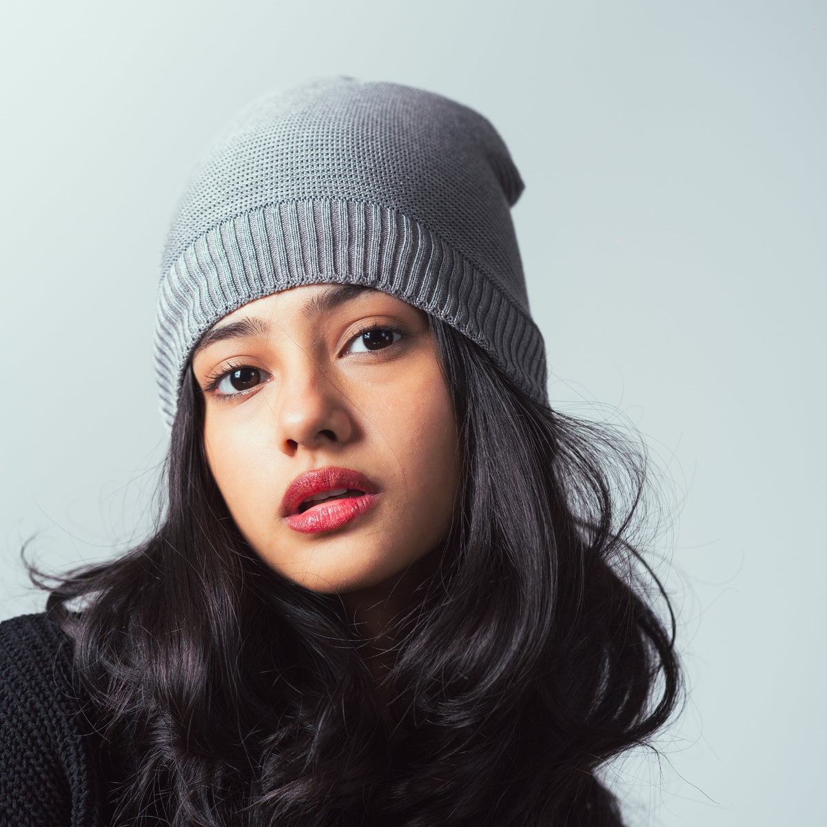 Woman wearing a gray knit beanie against a light background