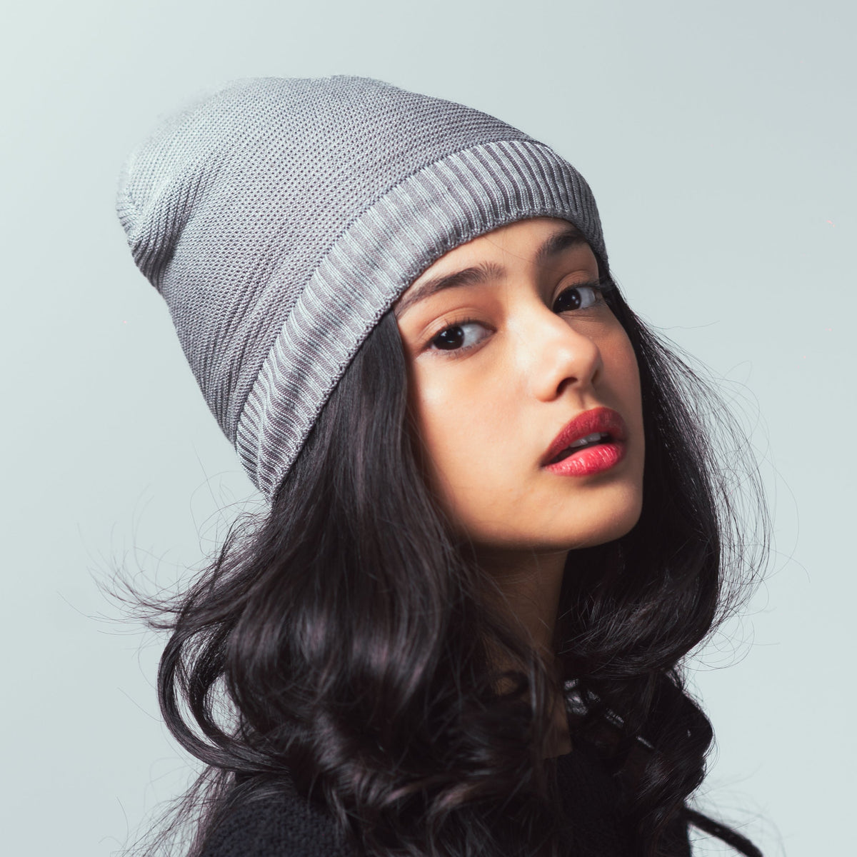 Woman wearing a gray beanie against a light gray background
