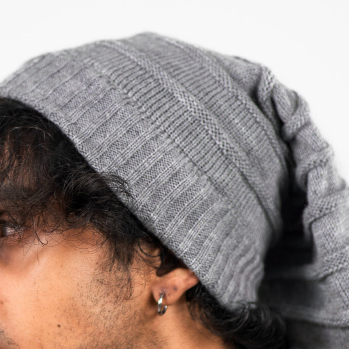 Person wearing a gray knit beanie with a neutral background