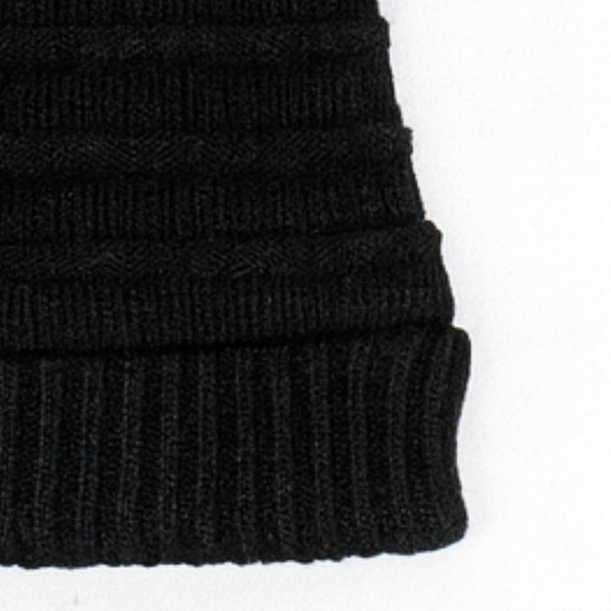 Close-up of a black knit beanie on a white background