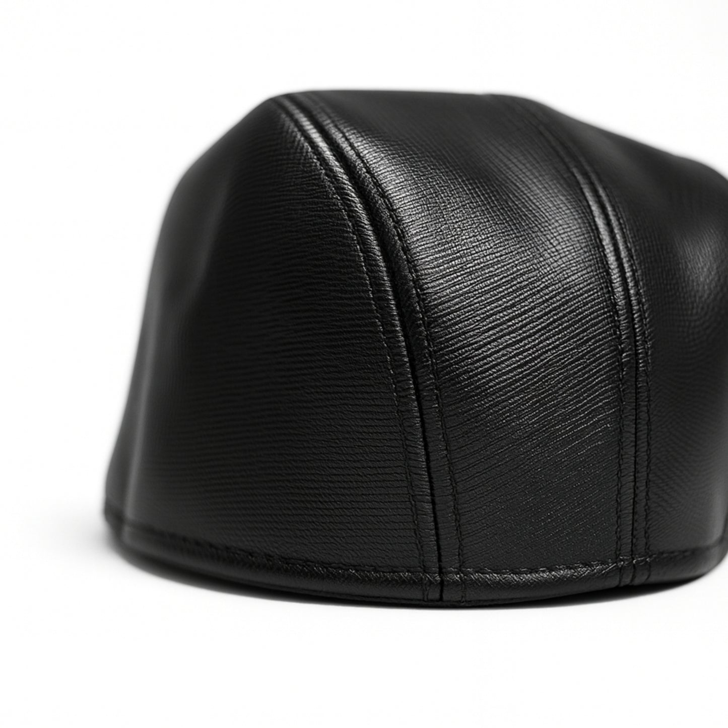 Black faux leather flat cap with a structured low crown , stiched curved in the middle and an adjustable round back photographed on a white background.

