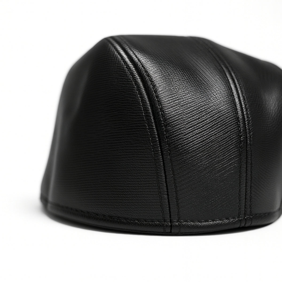Black faux leather flat cap with a structured low crown , stiched curved in the middle and an adjustable round back photographed on a white background.
