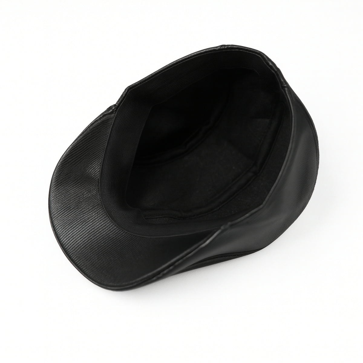 Black faux leather flat cap with a structured low crown , stiched curved in the middle and an adjustable round back photographed on a white background.
