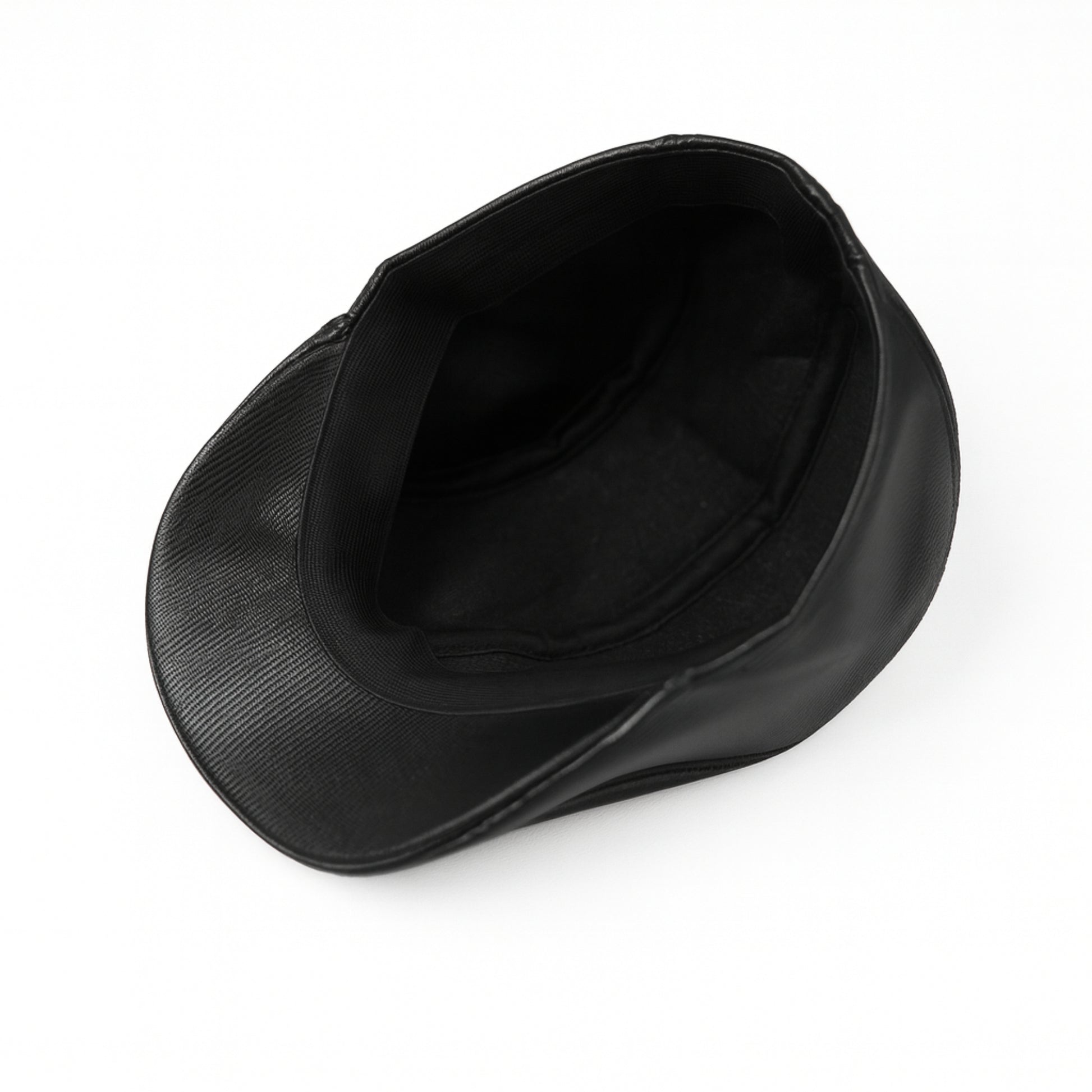 Black faux leather flat cap with a structured low crown , stiched curved in the middle and an adjustable round back photographed on a white background.
