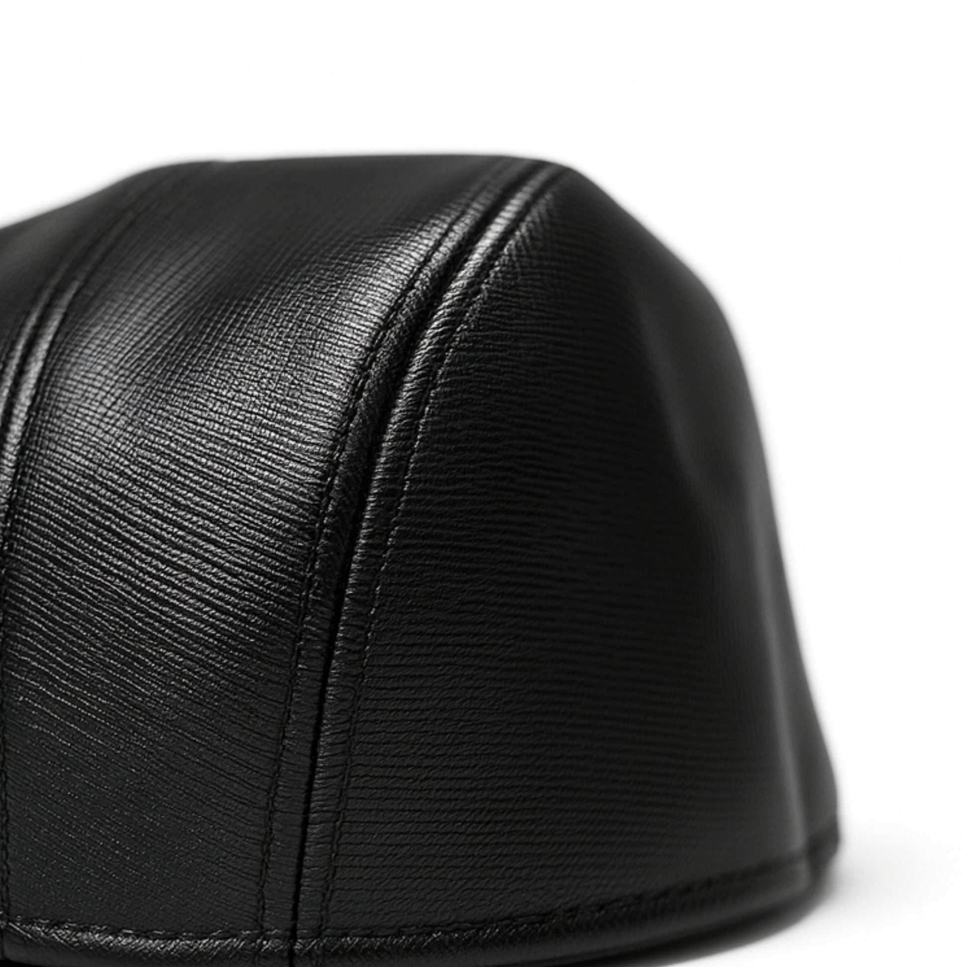 Black faux leather flat cap with a structured low crown , stiched curved in the middle and an adjustable round back photographed on a white background.
