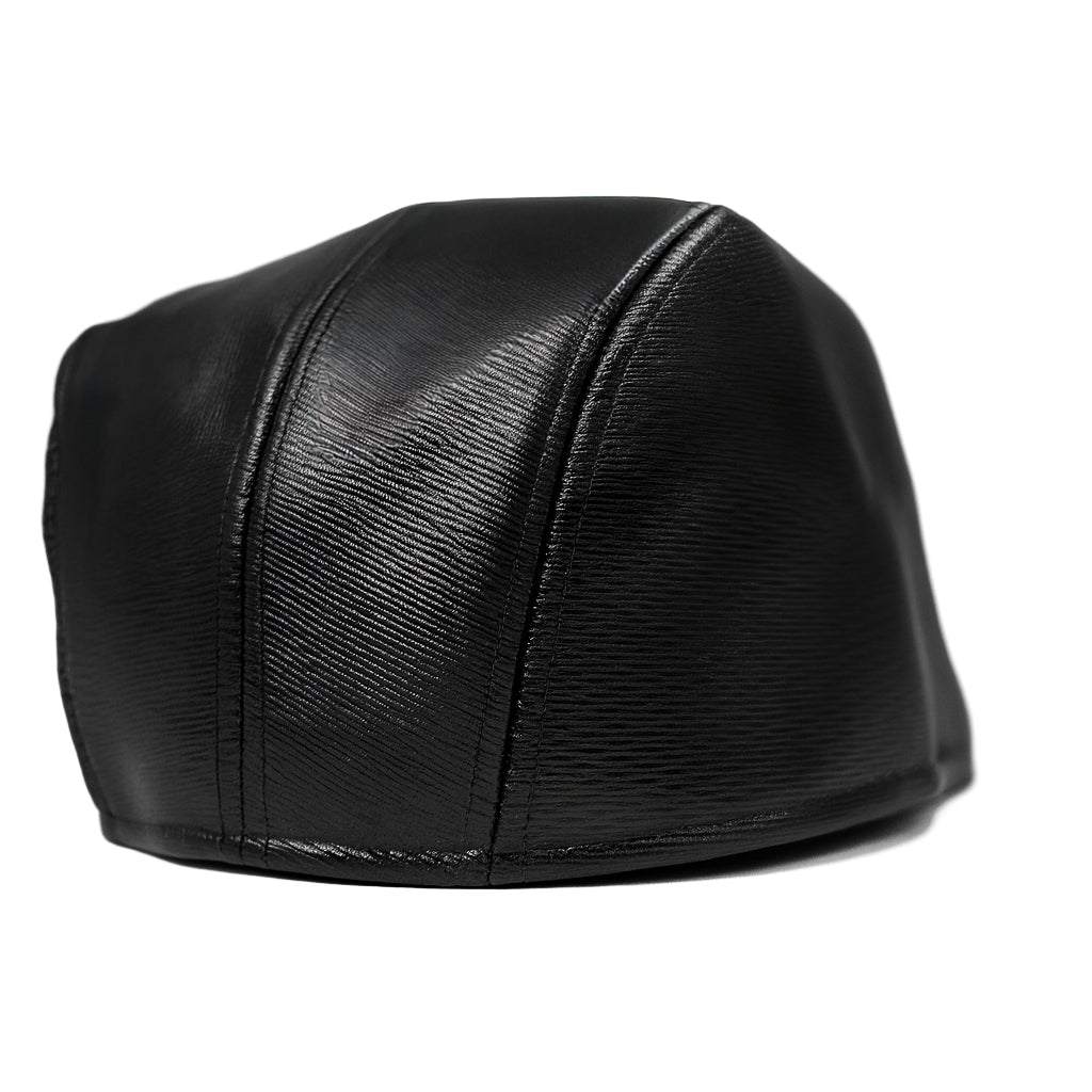 Black faux leather flat cap with a structured low crown , stiched curved in the middle and an adjustable round back photographed on a white background.
