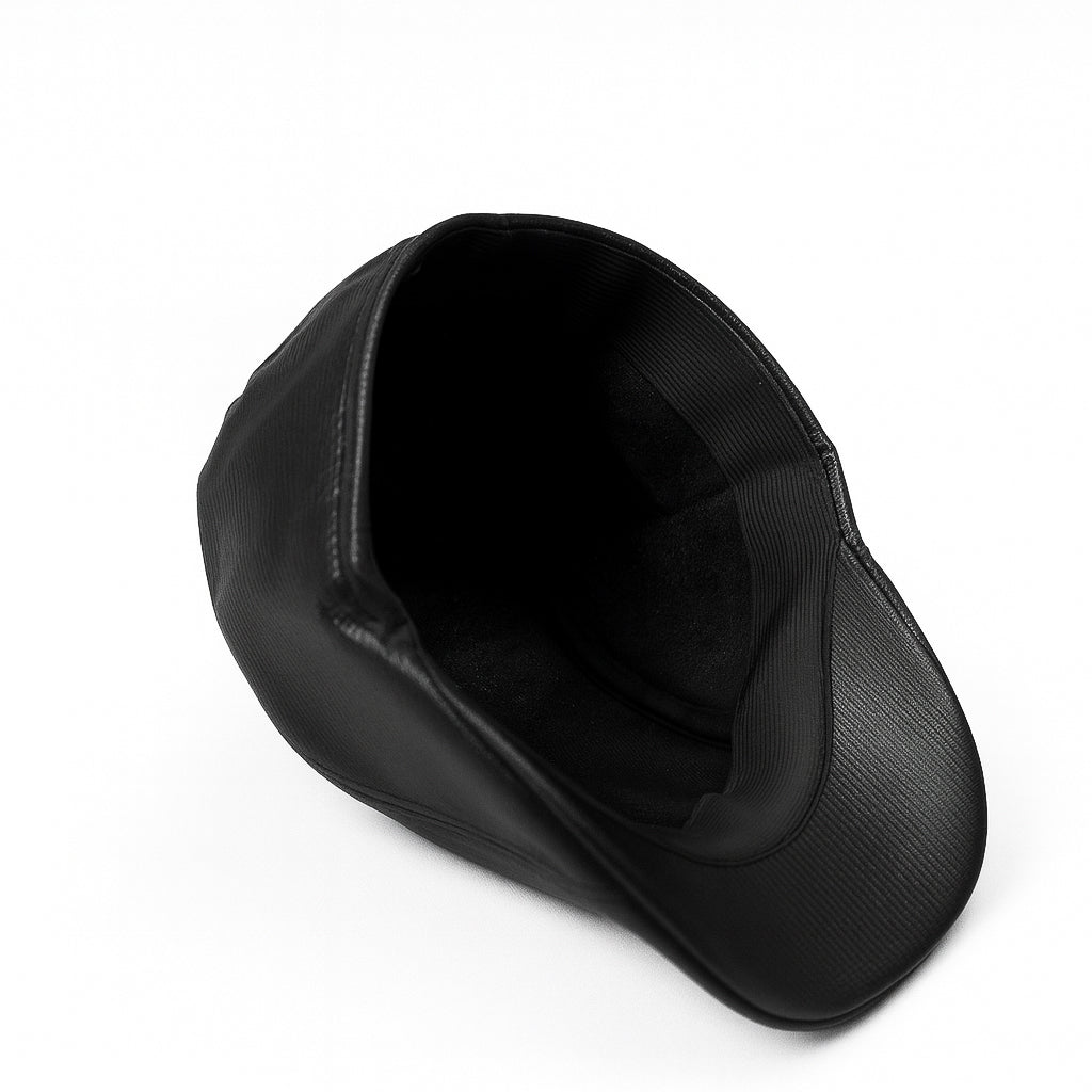 Black faux leather flat cap with a structured low crown , stiched curved in the middle and an adjustable round back photographed on a white background.
